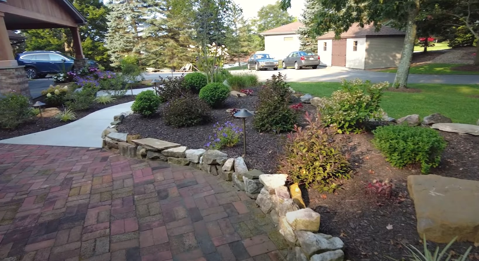 Beautiful landscaped front yard with stone pathways, lush plants, and professional hardscaping design