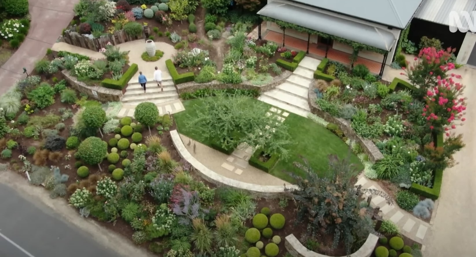 Aerial view of elaborate landscape design with curved pathways, topiary spheres, and diverse plantings